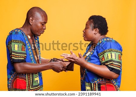 Broke african american aggressive man and woman having family dispute while discussing bankruptcy and money crisis. Angry wife shouting at husband about financial trouble while showing empty wallet Royalty-Free Stock Photo #2391189941