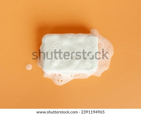 White Soap Bar, Body Care Cosmetic, Fruit Flavored Soapy Detergent, Solid Shampoo, Red Translucent Glycerin Soap on Orange Foamy Background Royalty-Free Stock Photo #2391194965