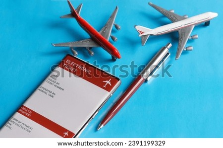 An electronic air ticket form on the screen of a mobile phone next to toy passenger airplanes and a pen. The concept of buying and using an electronic air ticket for travel. Photo. Close-up