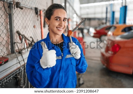 Portrait of woman auto mechanic working at car repair shop with looking at camera.