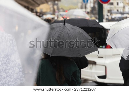 picture of a crowd of people with umbrellas walking in the city in the rain