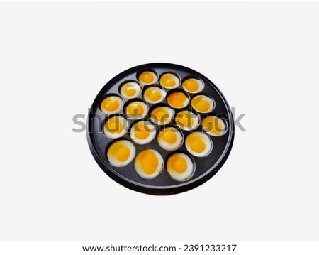 The white background in the picture is a black pan. There are a number of fried quail eggs in the black pan. The quail eggs are white and yellow in the middle.