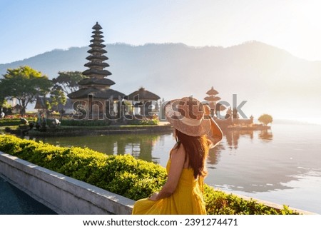 Young woman tourist relaxing and enjoying the beautiful view at Ulun Danu Beratan temple in Bali, Indonesia Royalty-Free Stock Photo #2391274471