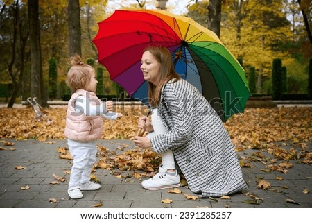 Mother and cute baby girl walking in autumn park with leaves on the ground. Mom spending time with a small child in the park. ?oncept of a good mother-child relationship.