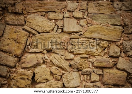 Close-up of Textured Stone Wall with Brickwork and Wood Detail. Textured stone wall with wood and brickwork patterns.