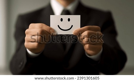  Professional person with a Smiley card. A man in a suit holding up a smiling card. A Businessman holding up a smiley face card.