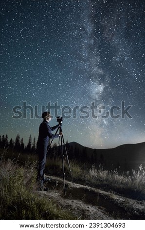 Professional photographer taking photos of Milky Way. Young male focusing his camera to take perfect picture of starry sky. Male taking pictures of night sky full of stars in mountains.