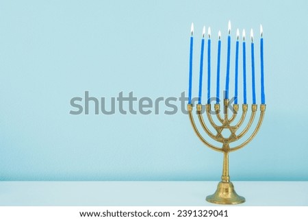 Menorah with burning candles on white table near blue wall, closeup. Hanukkah celebration Royalty-Free Stock Photo #2391329041