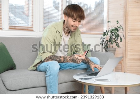 Tattooed young man with credit card using laptop at home