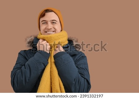 Young man in winter clothes on brown background
