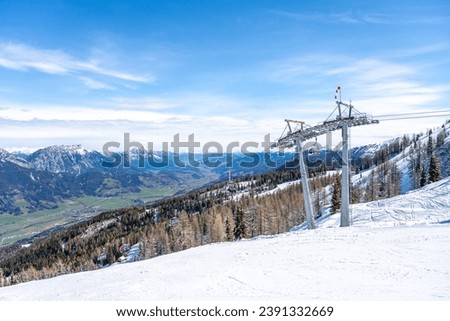 Ski lift in alpine ski resort. Late winter snow in the mountains and green grass in the valley. Schladming, Austria