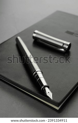 Stylish fountain pen, cap and leather notebook on light grey textured table, closeup Royalty-Free Stock Photo #2391334911