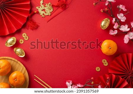 Get glimpse of festive fervor with top view photograph showcasing fans, traditional coins, sycee, Hong Bao, wall hanging, tangerines, sakura on red backdrop, creating space for your text or promotion