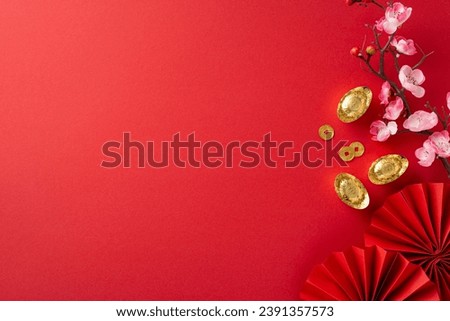 Immerse yourself in Chinese New Year ambiance through this top-view arrangement featuring fans, Feng Shui items, symbolic coins, sycee and sakura blooms on red setting, ready for text or advertising Royalty-Free Stock Photo #2391357573