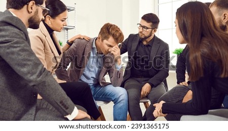 Businessman is upset about failed project and shares his problem with colleagues who comfort him. Employees express their condolences and make gesture of comfort for man who is worried about dismissal Royalty-Free Stock Photo #2391365175