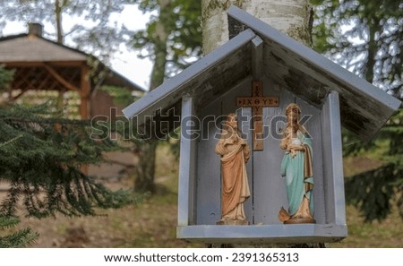 A shrine on a birch trunk. Virgin Mary with baby Jesus in her arms and Jesus risen from the dead.Forest shrine on a tree. Inside there is a cross with Greek inscriptions. 