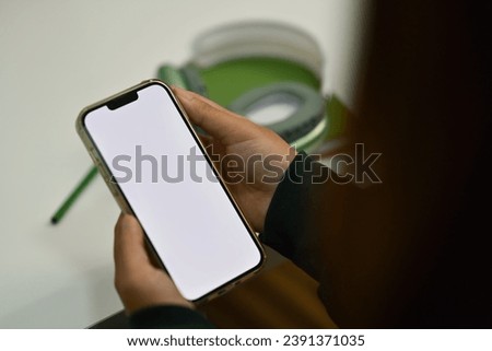 Woman using mobile phone at office desk. White screen for your advertising text message