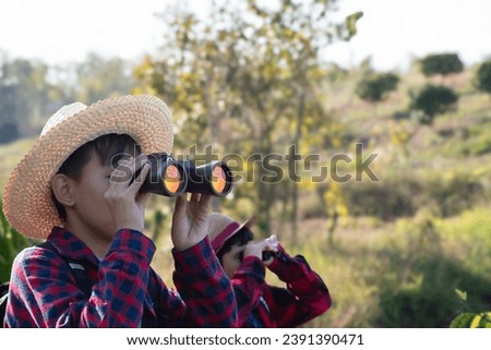 Asian schoolboy is taking his long summer vacation with his friend by doing the birdwatching, learning the habitat, rally walking and trekking in the forest, new edited. Royalty-Free Stock Photo #2391390471