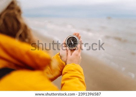 Woman traveler looking for directions with a compass on the beach by the sea. Active lifestyle. Adventure concept. Royalty-Free Stock Photo #2391396587