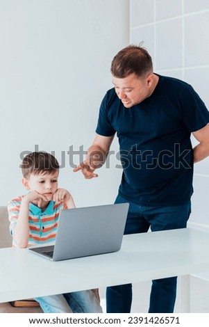 Male teacher teaches child at desk with laptop
