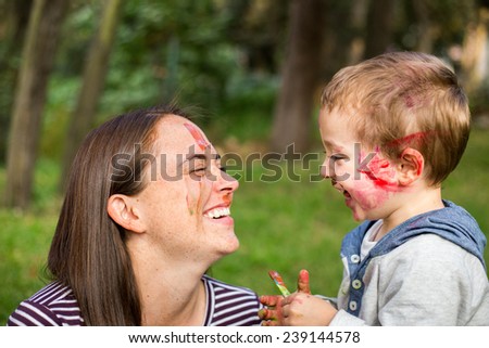 Happy mother painting her childÃ?Â´s face in the park.