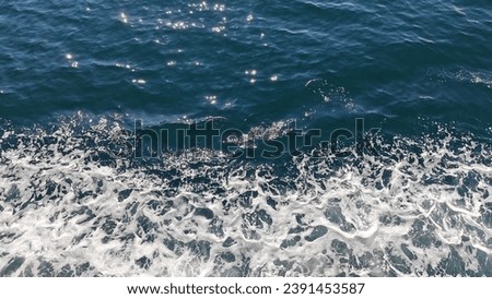 White water waves above the surface of the turquoise sea are beautiful and clean. The white water waves are caused by the breaking of the water by ships sailing in the sea. Water surface texture