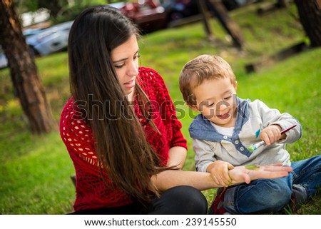 Happy child painting his motherÃ?Â´s hand in the park.