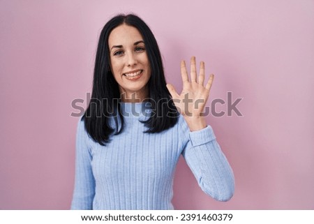 Hispanic woman standing over pink background showing and pointing up with fingers number five while smiling confident and happy. 