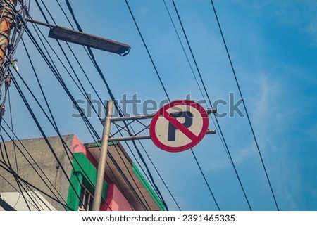 a no parking sign with messy wires in the background