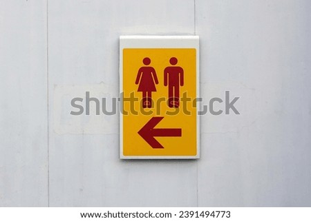 A yellow male and female toilet sign on the white wall.