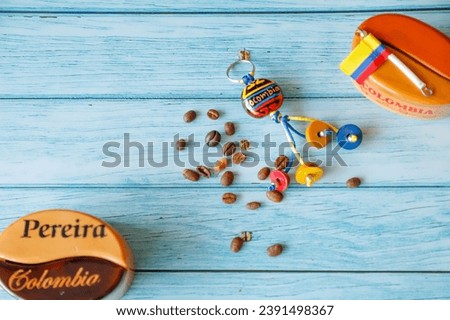 A blue background featuring a collection of Colombian coffee beans, souvenirs and the Colombian flag.