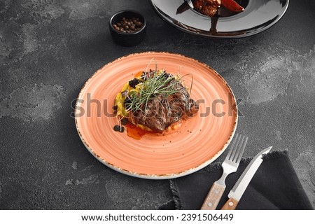Juicy beef steak resting on a bed of creamy sweet potato puree, elegantly served on a ceramic plate against a stark black background.