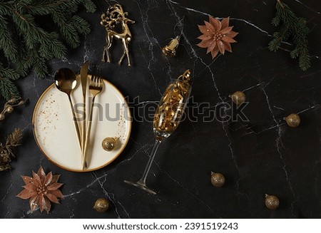 Christmas table setting, New Year's cutlery with a napkin on a plate on a marble concrete background, festive composition with fir branches and a glass of champagne, kitchen background. 