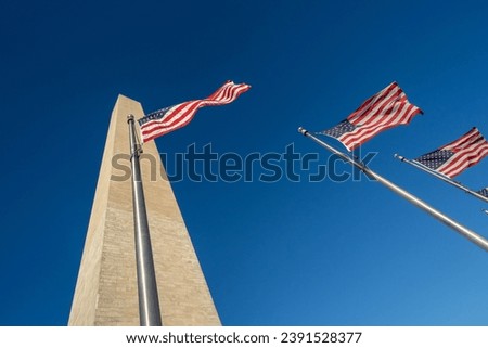 Several American flags and the Washington Monument, looking up