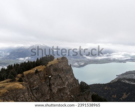 Picturesque panorama of Lake Thun on a cloudy and rainy Autumn day from Niederhorn Mountain ridge in Swiss Alps