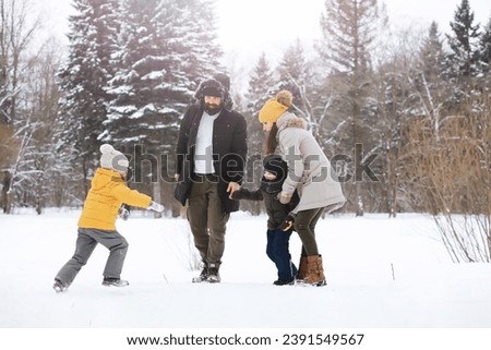 Happy family playing and laughing in winter outdoors in snow. City park winter day.