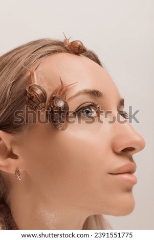 Beautiful woman with snails on her face. Cosmetology procedures, skin rejuvenation. High quality photo