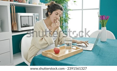 Young pregnant woman having breakfast using laptop at dinning room Royalty-Free Stock Photo #2391561327