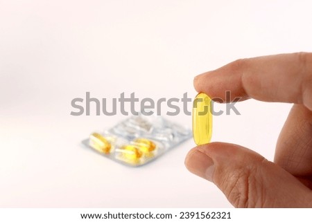 A man holds a polyunsaturated fatty acid complex capsule in his hand. Prevention and treatment of ischemic heart disease, atherosclerosis of cerebral vessels. Royalty-Free Stock Photo #2391562321