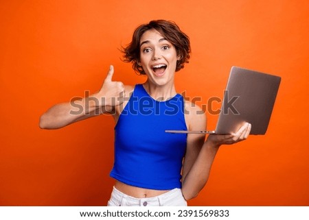 Photo of funky excited girl dressed blue top thumb up texting modern gadget isolated orange color background