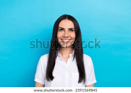 Photo of positive cheerful lady wear white shirt smiling looking up empty space isolated blue color background