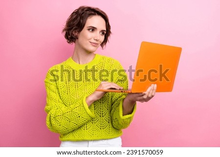 Photo of girl in yellow knitwear jumper hold netbook surfing social networks to search design variation isolated on pink color background