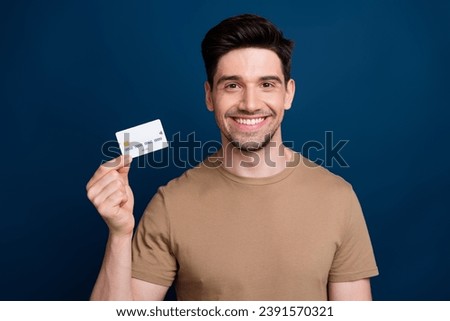 Photo of nice joyful man wear beige trendy clothes hold plastic bank card isolated on dark blue color background