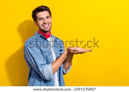 Photo portrait of nice young man palms hold empty space wear trendy jeans garment isolated on yellow color background
