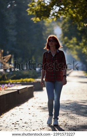 A fashionable Silhouette of redhead woman walking an autumn evening in the city