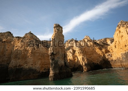 stunningly beautiful rocks in ocean near coast of Algarve in Portugal at sunset golden sun rays . Lagos,Porugal