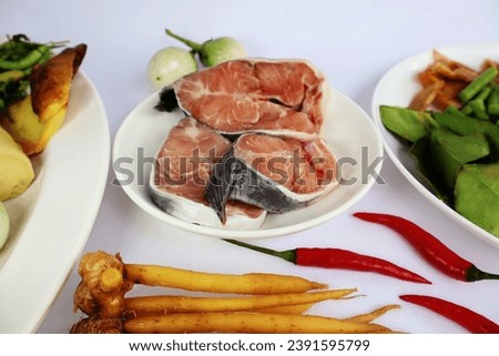 Fresh cut catfish with spices to prepare the menu Catfish in Fermented Fish Broth placed on a white background.

