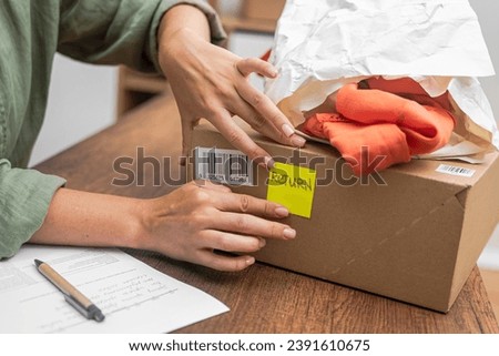woman online shopper affixes a barcode sticker to a cardboard box, marking it for return and refund.  Royalty-Free Stock Photo #2391610675