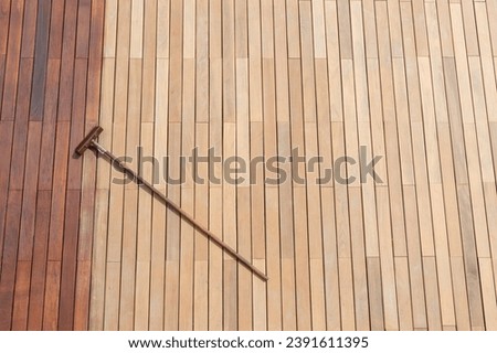 Freshly painted terrace hardwood floor with deck stain brush, oil application tool, and wood planks texture, high angle view, copy space concept Royalty-Free Stock Photo #2391611395
