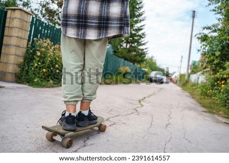 Beautiful teen girl in a plaid shirt riding a skateboard